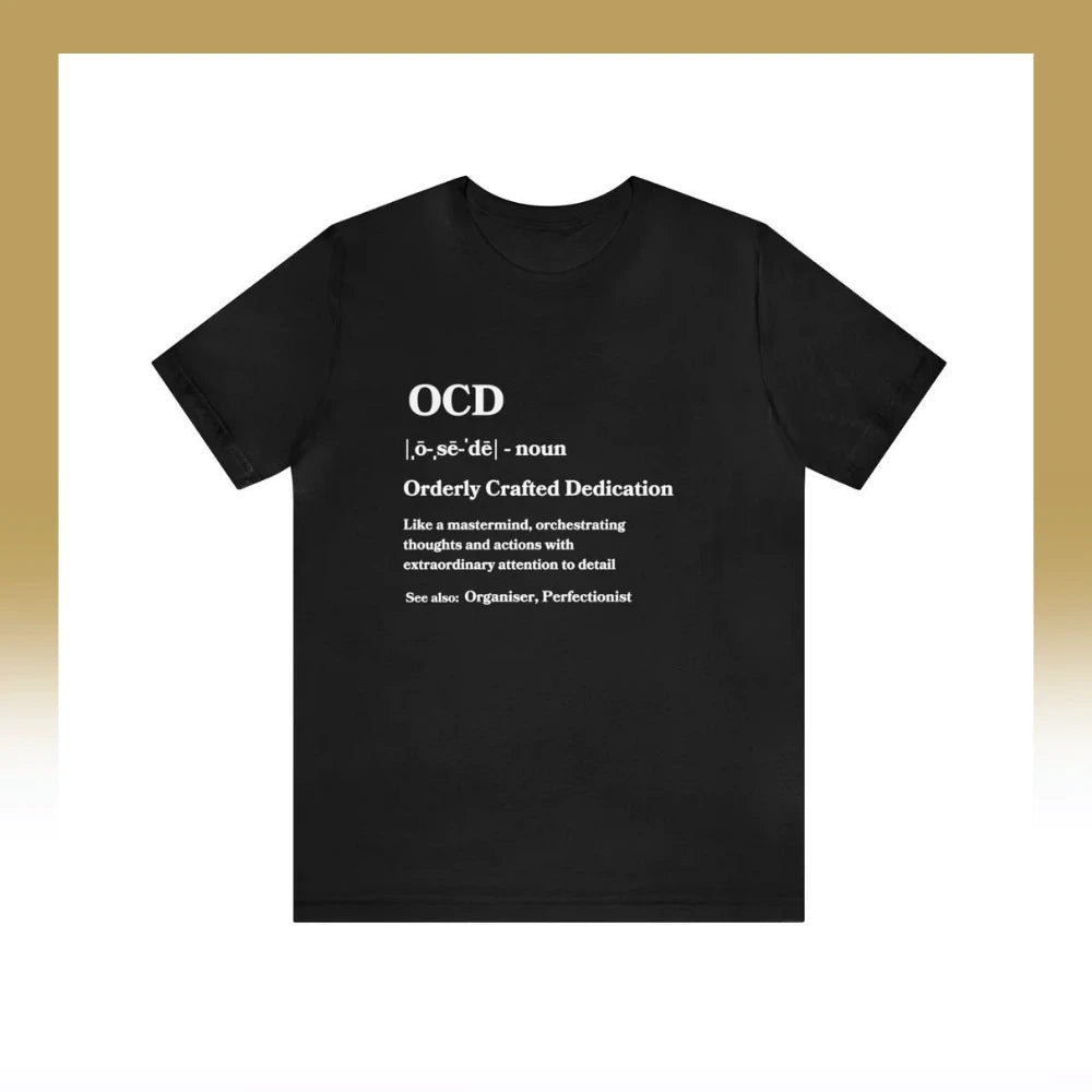 A black t-shirt with a creative definition of OCD printed on it in white text, redefining the acronym as "Orderly Crafted Dedication," highlighting attributes of meticulousness and attention to detail
