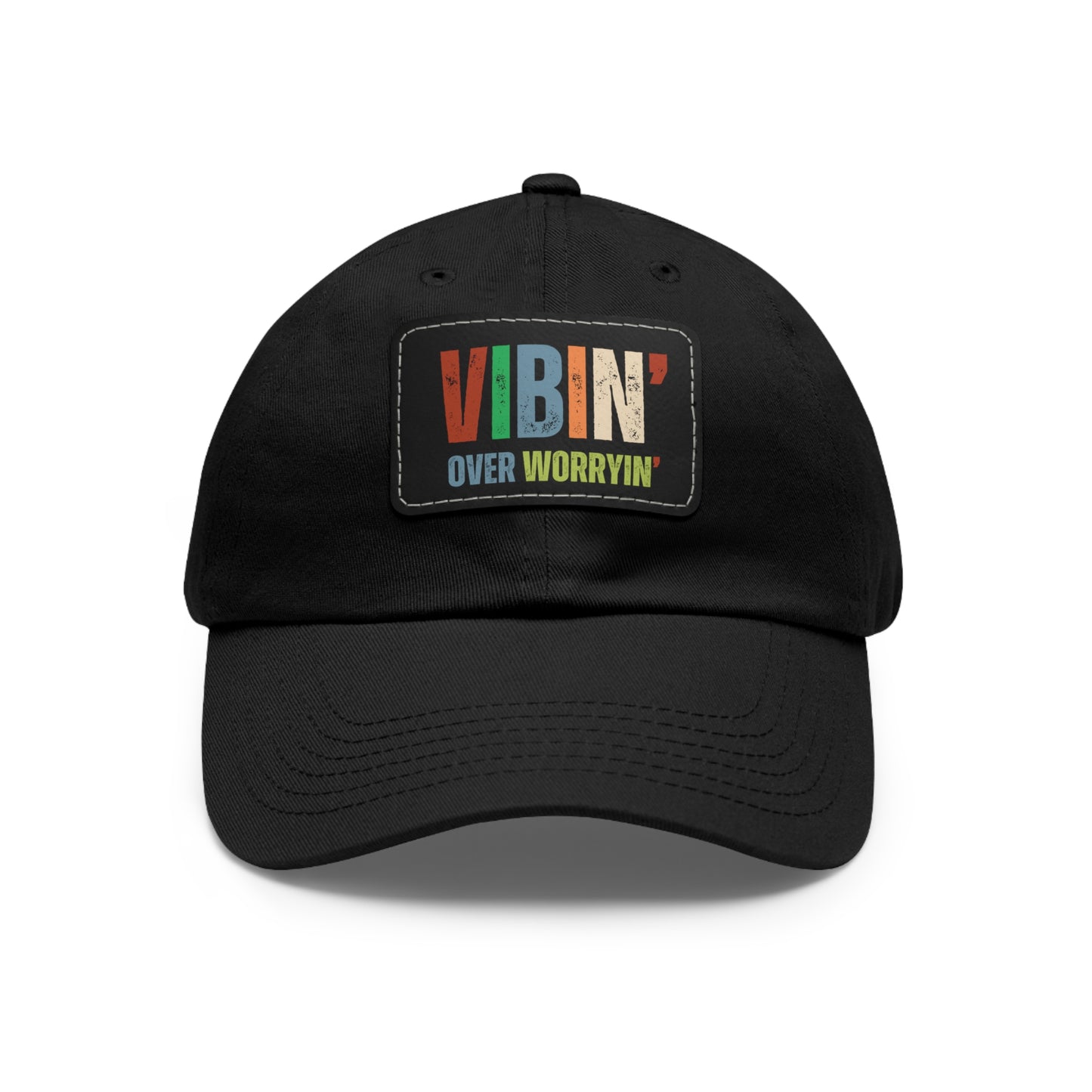 A black baseball cap with the Vibin' Over Worryin' Unisex Hat patch in bold letters.