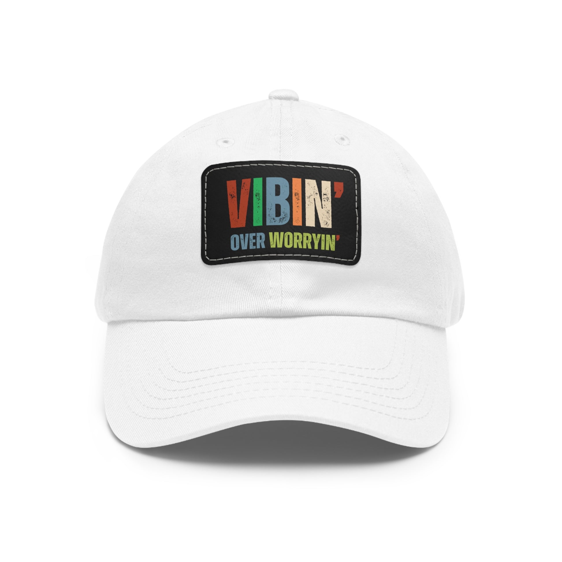 A black baseball cap with the Vibin' Over Worryin' Unisex Hat patch in bold letters.