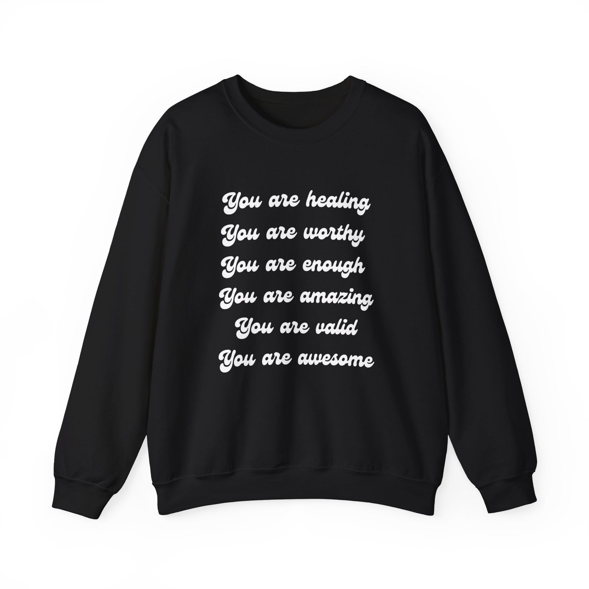 A person wearing a You Are Healing Unisex Crewneck Sweatshirt with an uplifting empowering message printed on it: "you are healing, you are worthy, you are enough, you are amazing, you are valid, you are awesome".