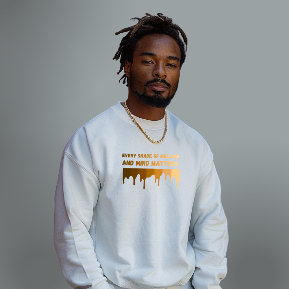 A man with dreadlocks wearing a white sweatshirt that reads "every shade of melanin and mind matters" stands against a grey background, presenting an inspirational message.