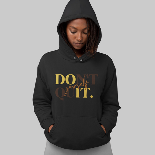 A person in a black DOn't quIT Yourself Unisex Hooded Sweatshirt with the uplifting quote "don't yourself quit." printed in golden letters on the front.