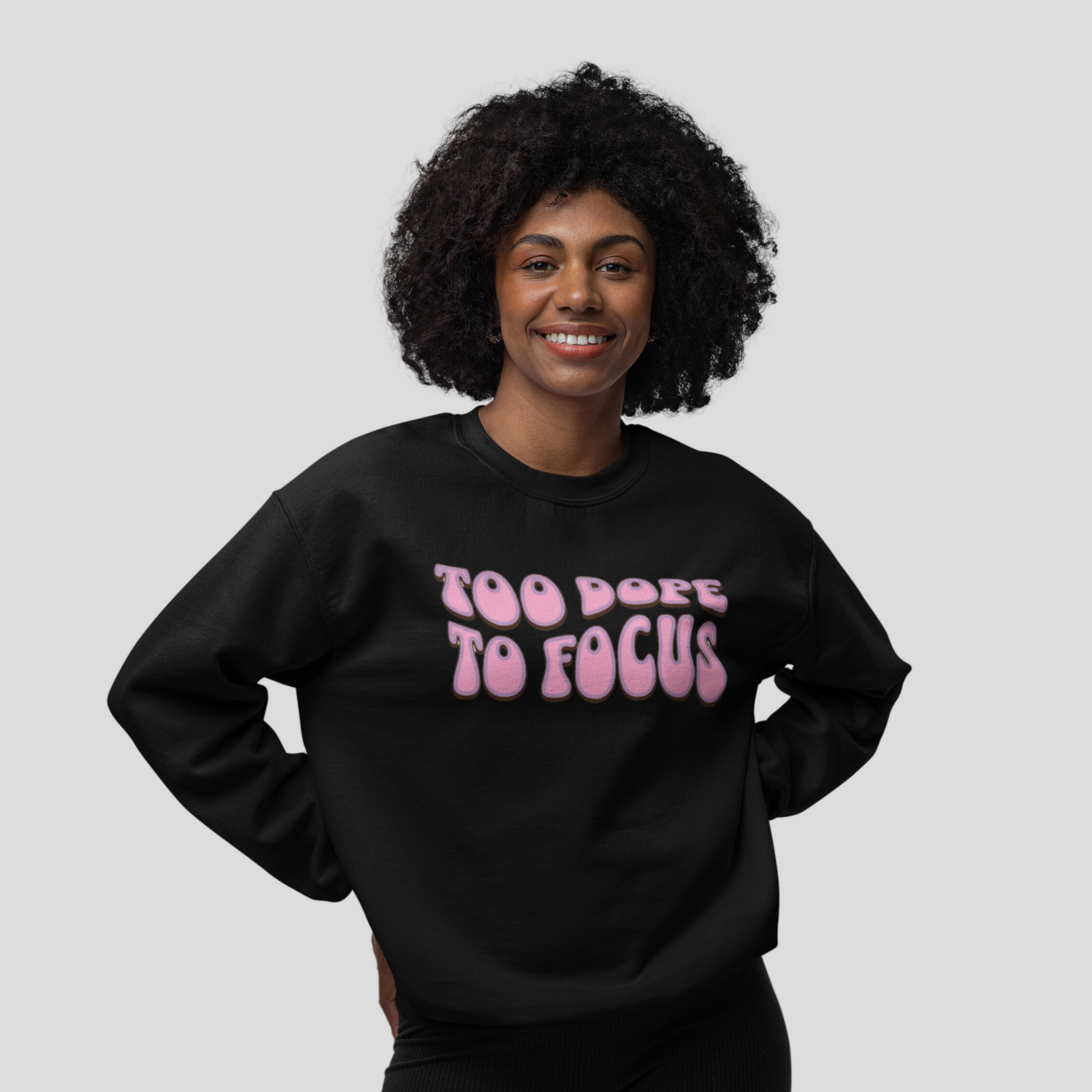 A woman with a bright smile, wearing a black sweatshirt with the phrase "Too Dope To Focus" in pink and white letters, promoting mental health awareness.