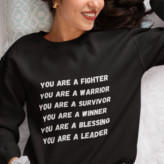 A smiling woman in a black You Are A Fighter Unisex Crewneck Sweatshirt with an empowering and supportive message.