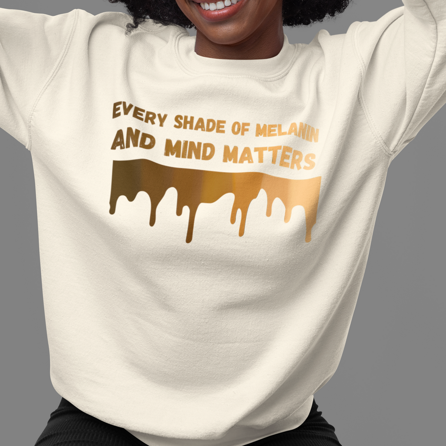 A joyful, supportive person wearing the Every Shade Of Melanin Unisex Crewneck Sweatshirt with a message that emphasizes the importance of diversity and mental health: "every shade of melanin and mind matters.